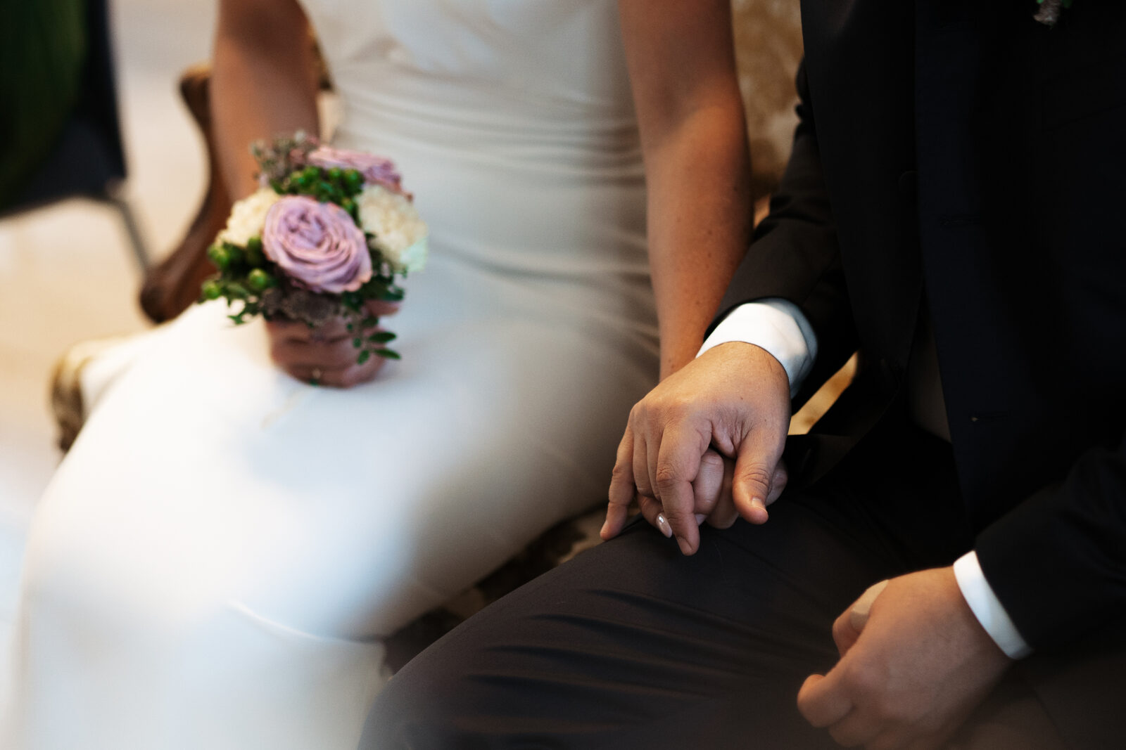Mains des mariés jointes, bouquet de roses dans les mains