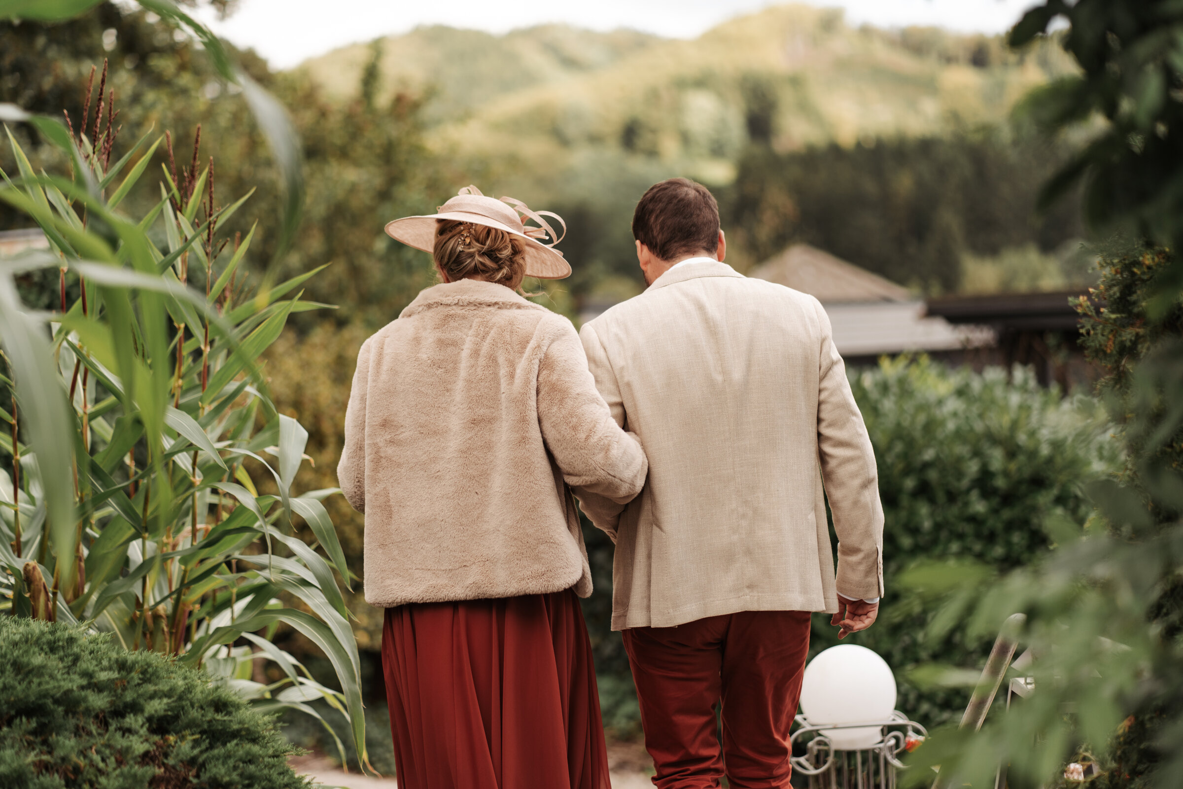 Couple de dos, bras dessus bras dessous, dans un jardin verdoyant